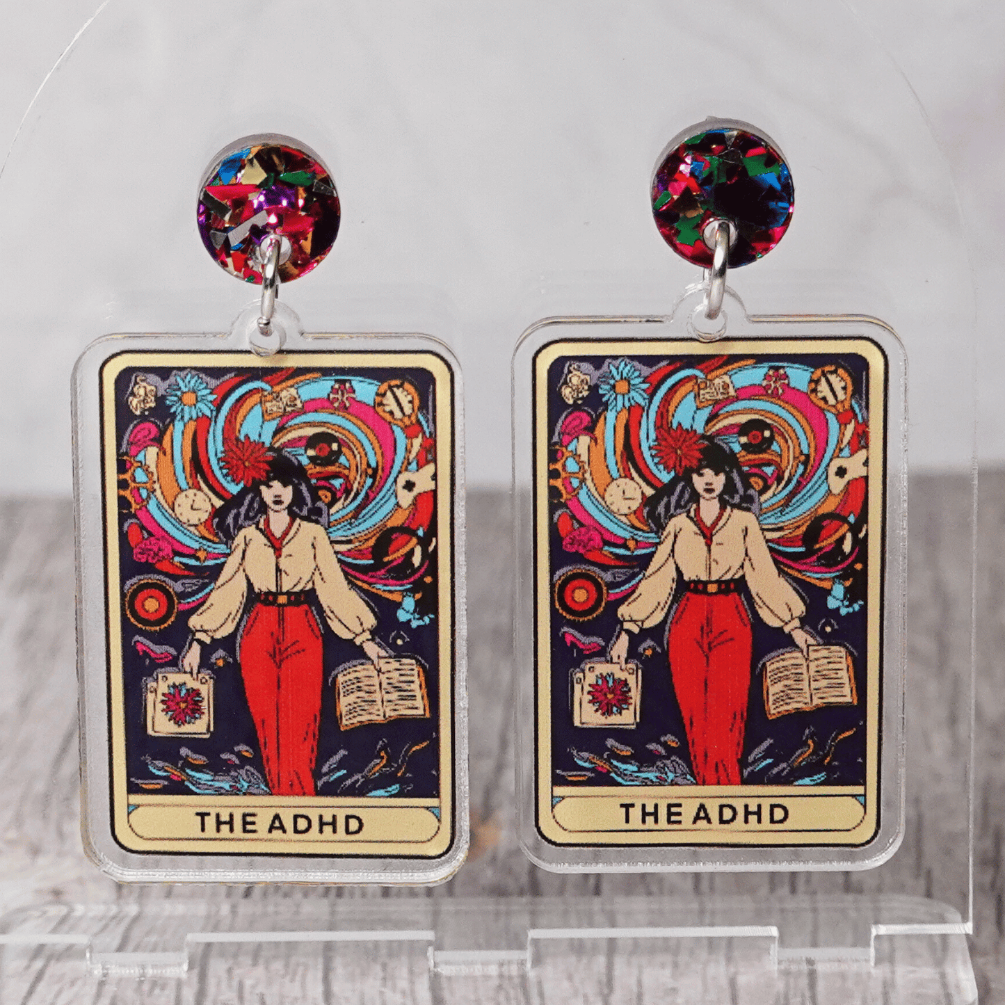 Acrylic dangle earrings featuring a colorful tarot-style card labeled “The ADHD” with a woman surrounded by swirling patterns and books.