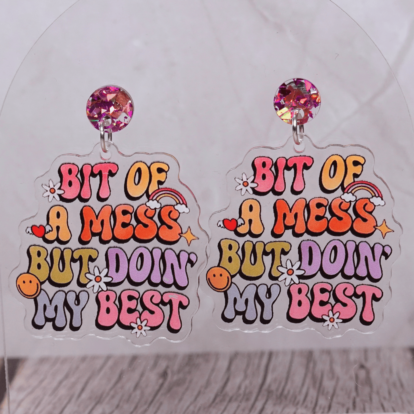 Colorful novelty dangle earrings with text “bit of a mess but doin’ my best”