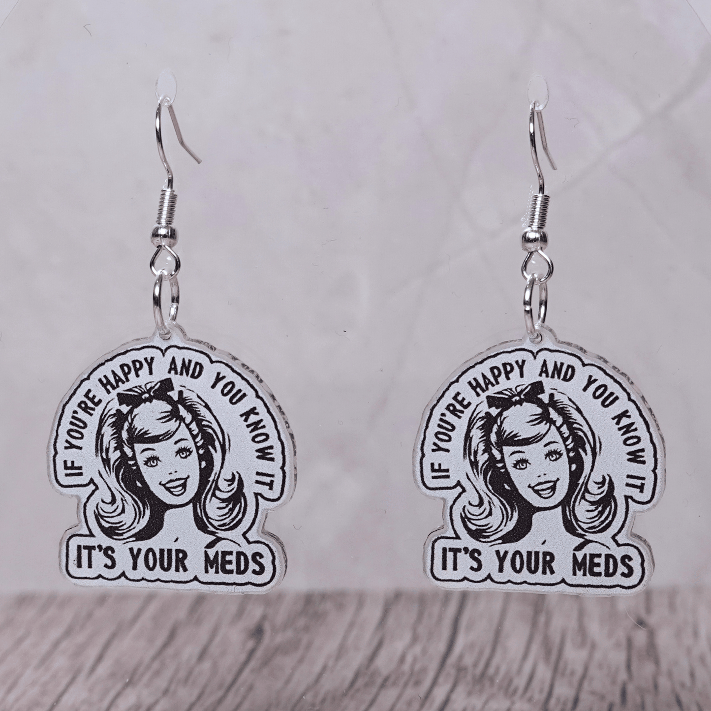 Black and white retro style earrings with woman illustration and text “If you’re happy and you know it it’s your meds”