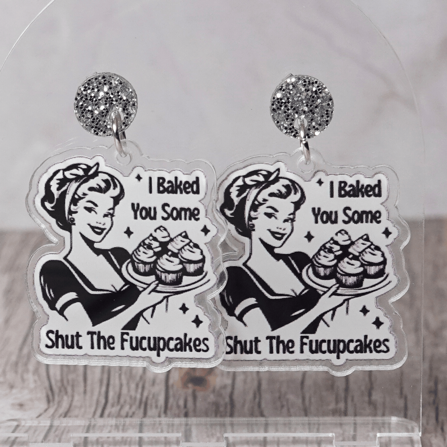 Retro style novelty dangle earrings with a vintage woman holding cupcakes and the phrase “I baked you some shut the fucupcakes”