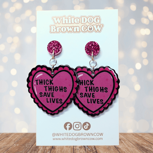 Pink heart dangle earrings with text “thick thighs save lives”