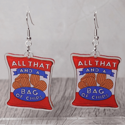 Acrylic dangle earrings shaped like a red potato chip bag that reads “All That and a Bag of Chips,” featuring illustrated chips and bold retro lettering.