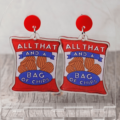 Acrylic dangle earrings shaped like a red potato chip bag that reads “All That and a Bag of Chips,” featuring illustrated chips and bold retro lettering.