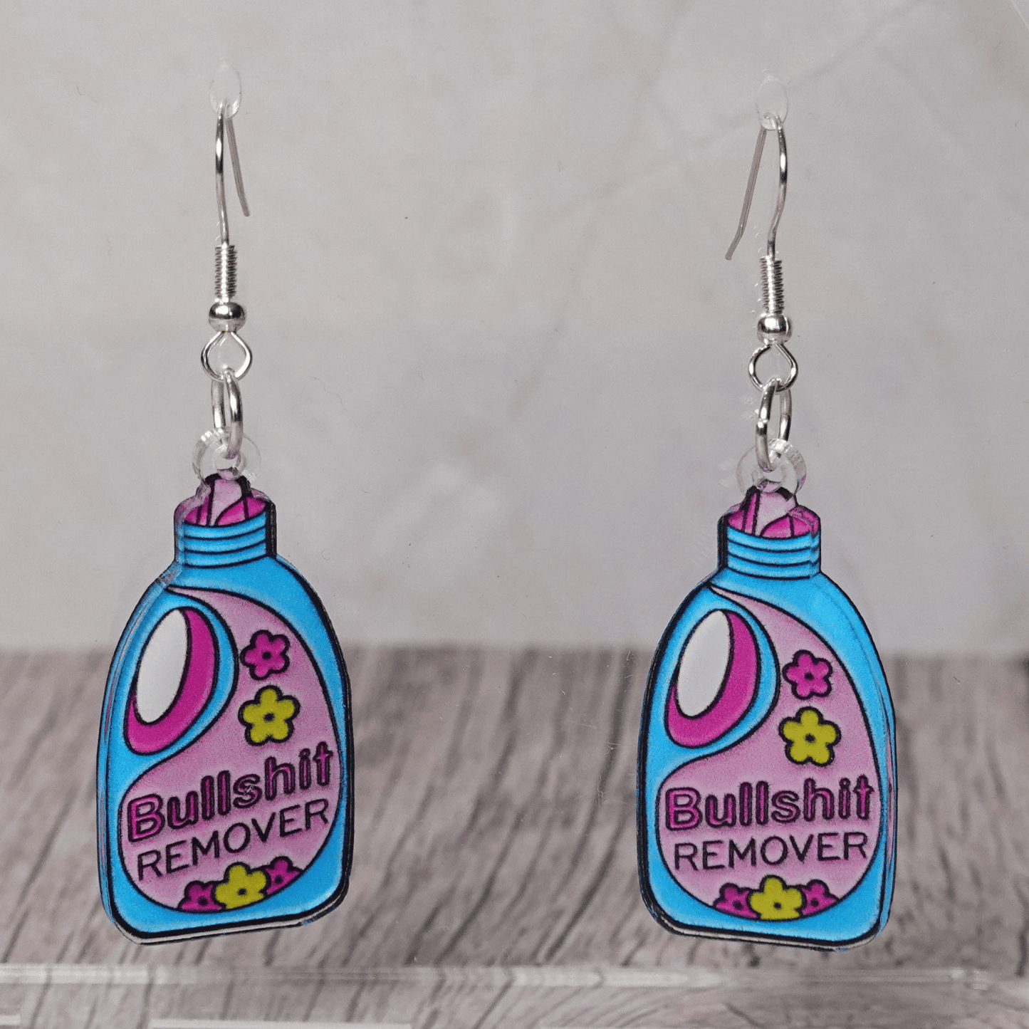 Colorful novelty dangle earrings shaped like a detergent bottle labeled “Bullsh*t remover”
