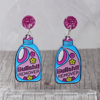 Colorful novelty dangle earrings shaped like a detergent bottle labeled “Bullsh*t remover” with glitter stud tops