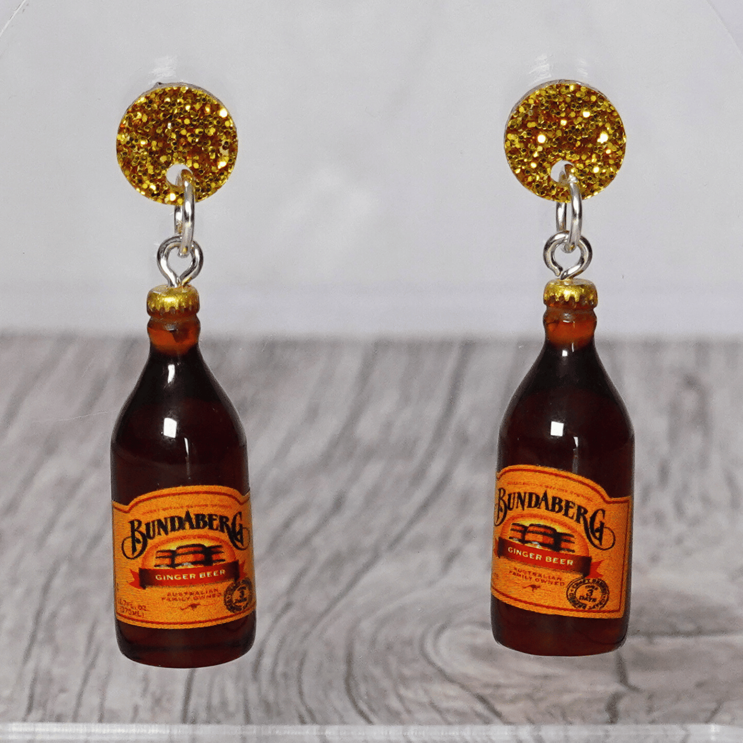 Mini brown ginger beer bottle shaped dangle earrings with orange labels and glitter studs