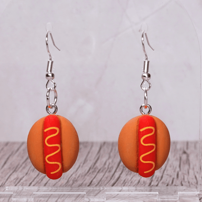 Novelty hot dog dangle earrings shaped like mini hot dogs with mustard detail on a bun and silver hooks.