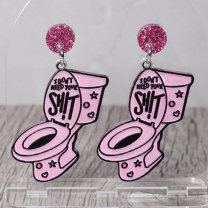 Pink novelty dangle earrings shaped like a toilet with text “I don’t need your sh*t” and glitter stud tops