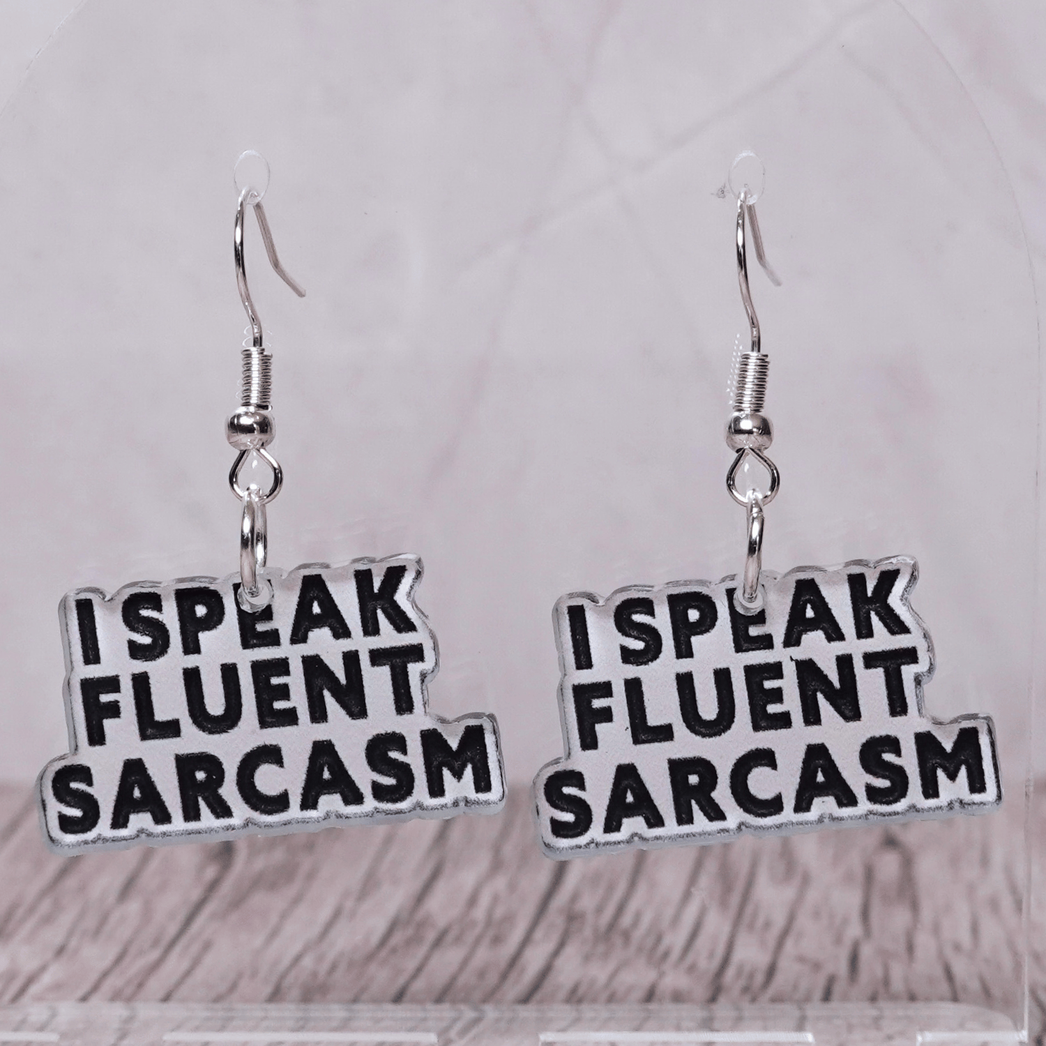 Black and white novelty earrings reading “I speak fluent sarcasm”