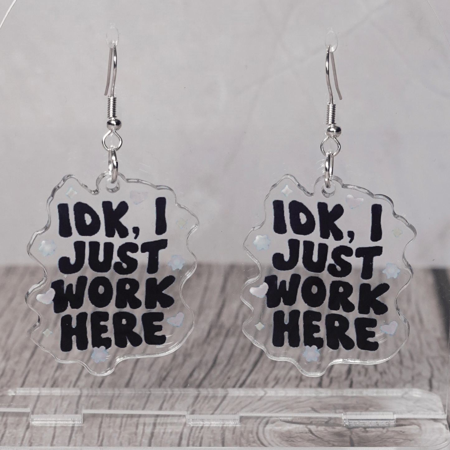 Clear acrylic dangle earrings with the phrase “IDK, I just work here” in bold black lettering