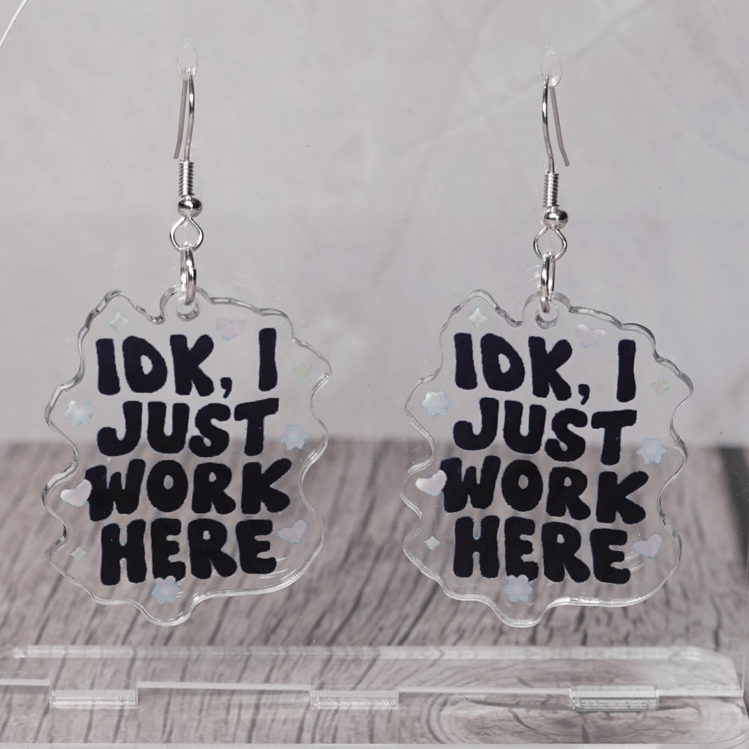 Clear acrylic dangle earrings with the phrase “IDK, I just work here” in bold black lettering