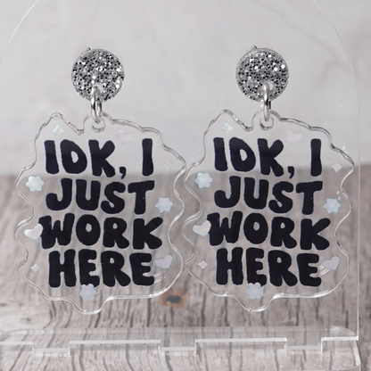 Clear acrylic dangle earrings with the phrase “IDK, I just work here” in bold black lettering