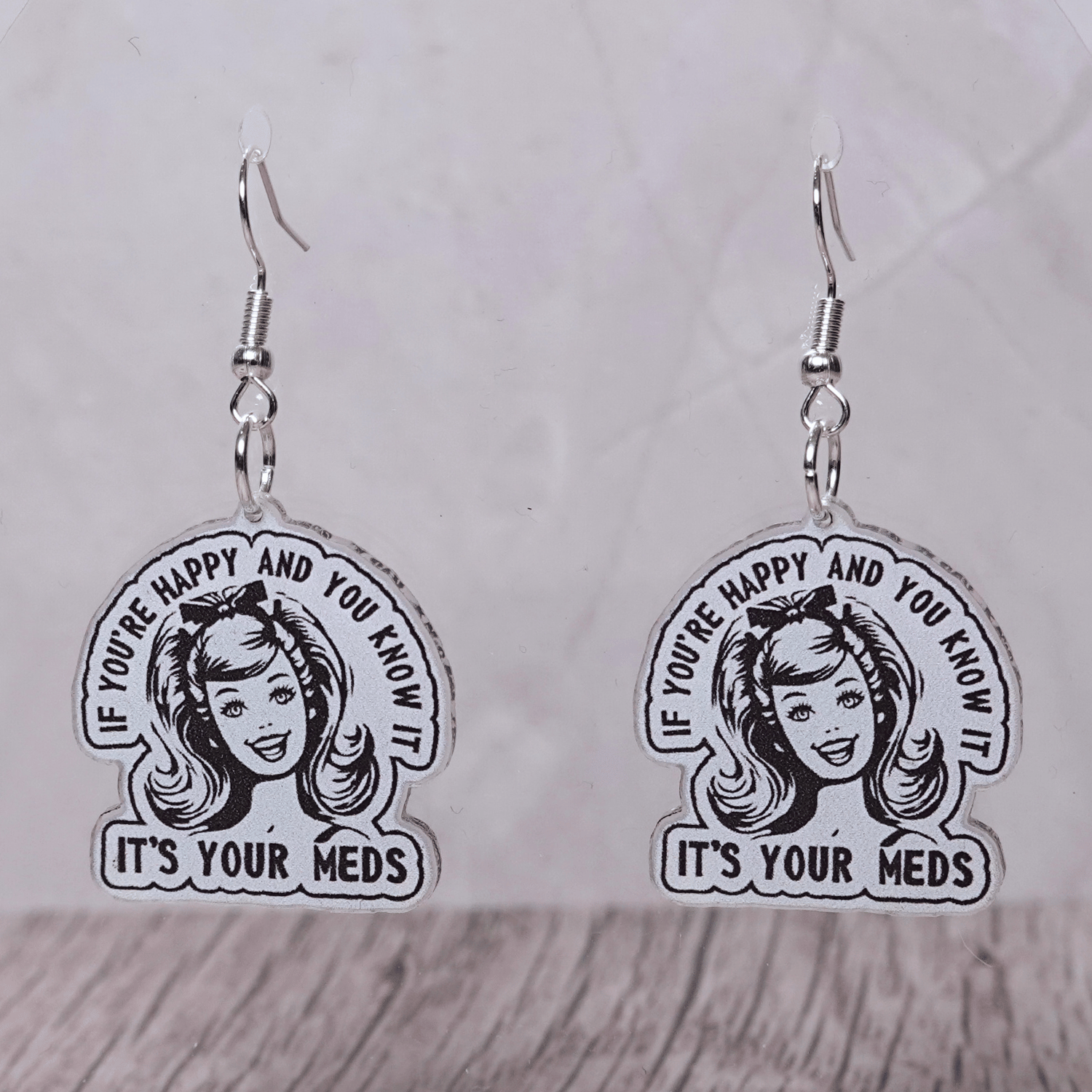 Black and white retro style earrings with woman illustration and text “If you’re happy and you know it it’s your meds”