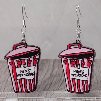 Acrylic dangle earrings shaped like a pink and red trash can labeled “Men’s Opinions”