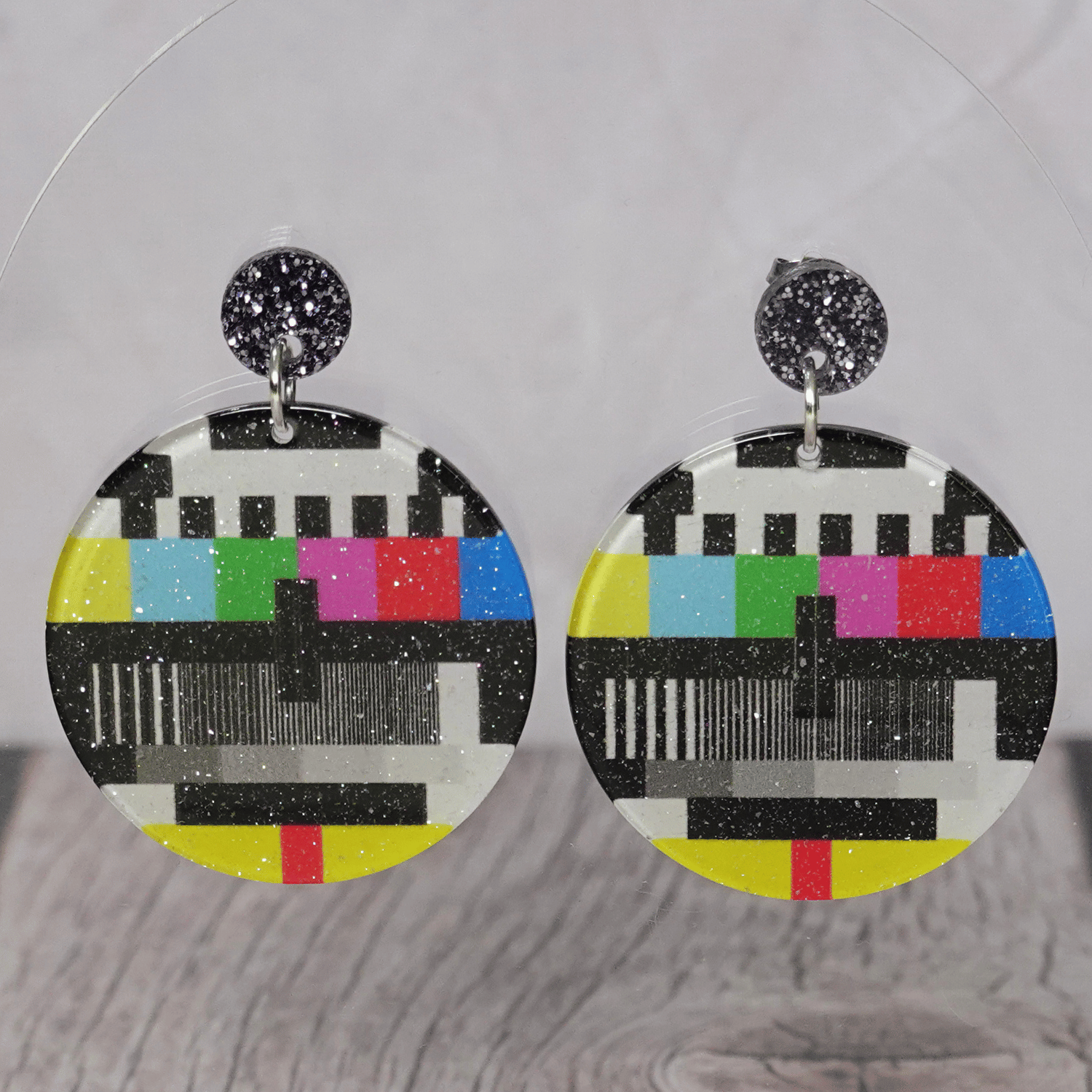 Round dangle earrings featuring a retro television test pattern with colorful bars and black and white graphics.