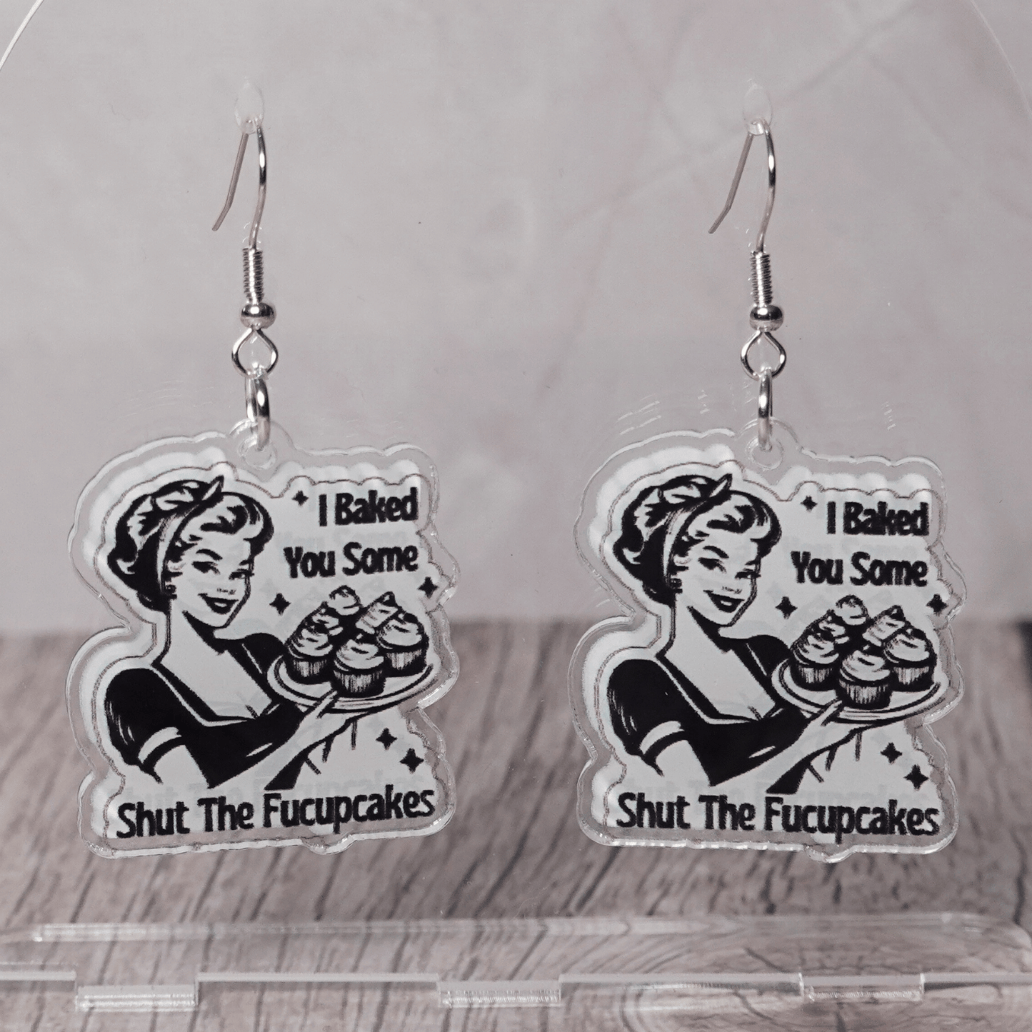 Retro style novelty dangle earrings with a vintage woman holding cupcakes and the phrase “I baked you some shut the fucupcakes”