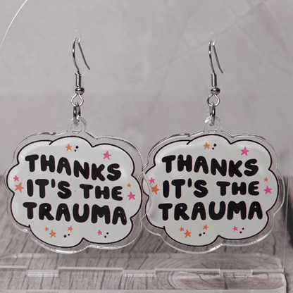 Clear acrylic dangle earrings with a speech bubble shape reading “Thanks it’s the trauma” with small star accents