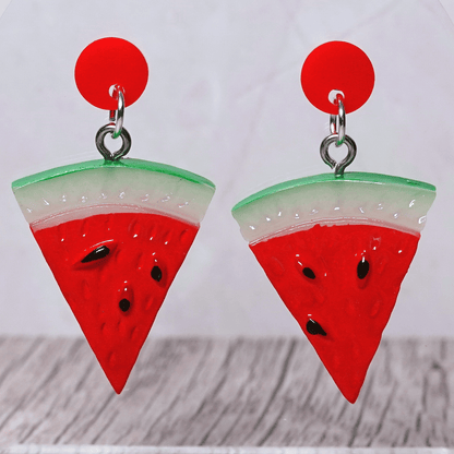 Watermelon slice dangle earrings shaped like red triangular watermelon pieces with green rind and black seed details on red stud tops
