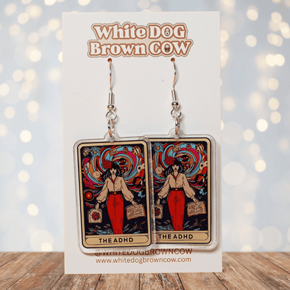 Acrylic dangle earrings featuring a colorful tarot-style card labeled “The ADHD” with a woman surrounded by swirling patterns and books.