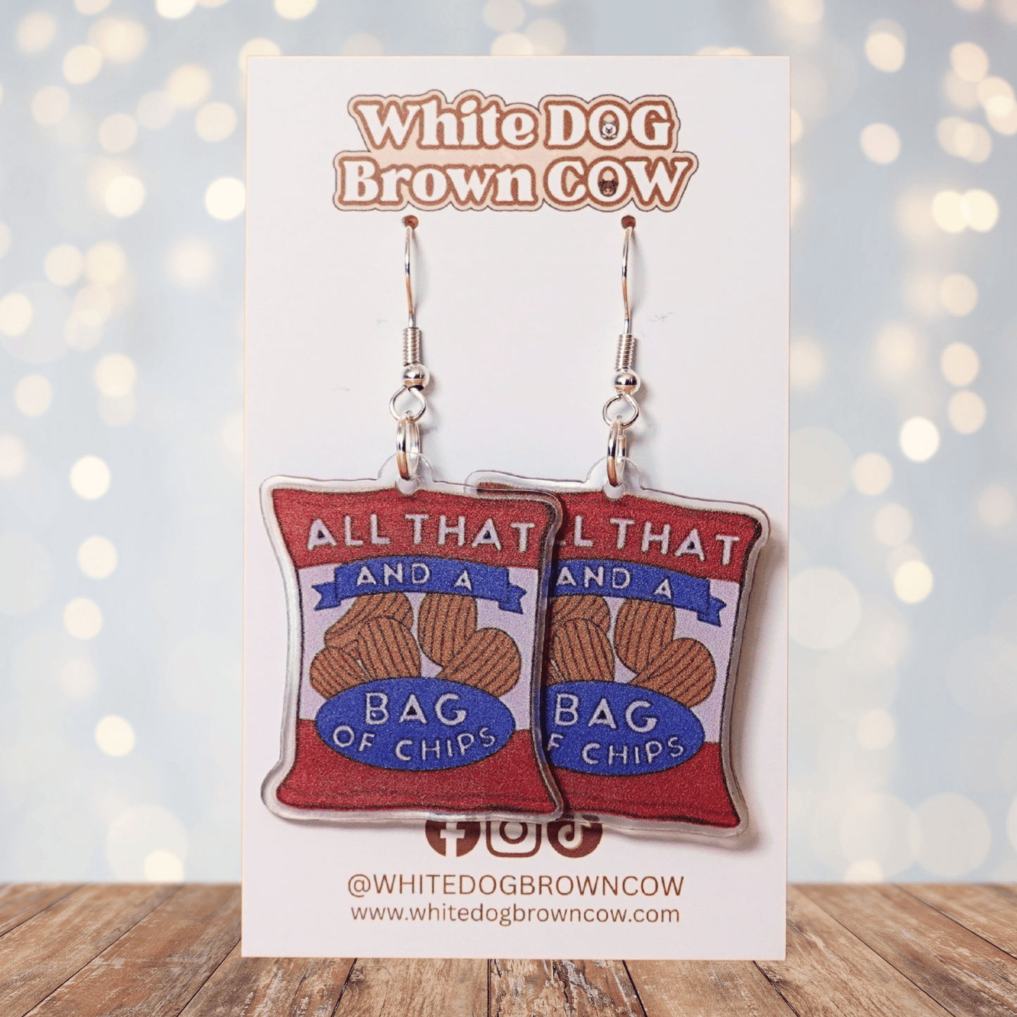 Funny acrylic dangle earrings shaped like a red chip bag that reads “All That and a Bag of Chips,” featuring illustrated potato chips and retro lettering.