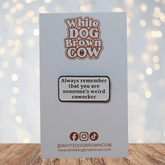 Rectangular enamel pin with the quote “Always remember that you are someone’s weird coworker” in black text on a white background.