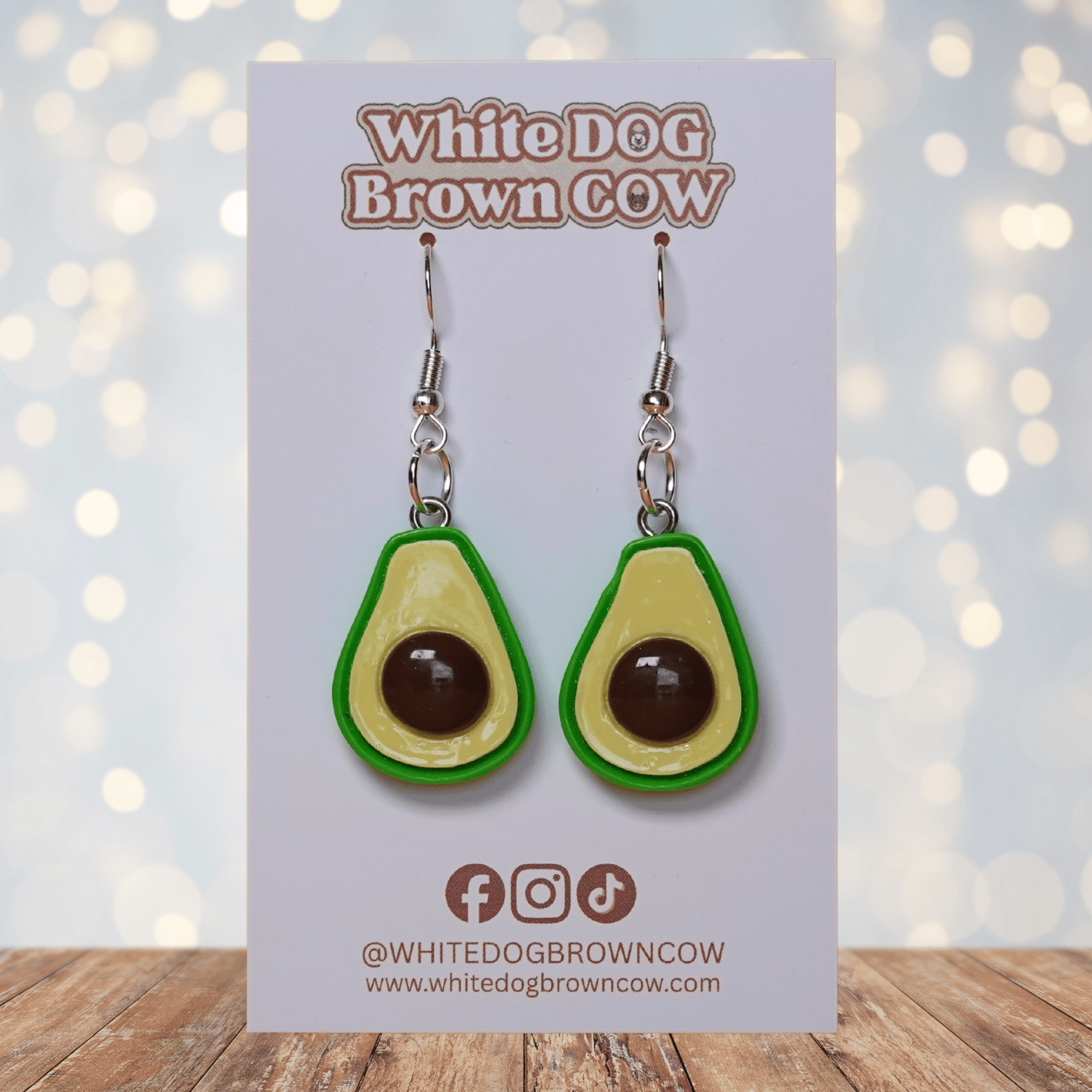 Avocado shaped dangle earrings with green outline, pale yellow center and raised brown pit on silver hooks.