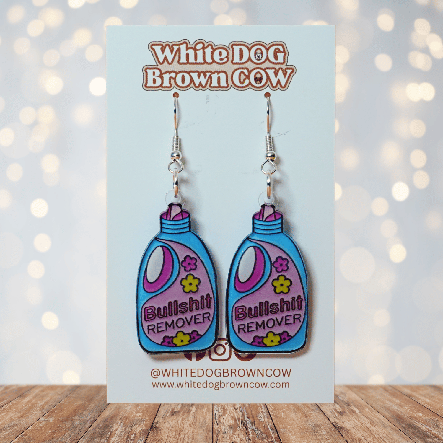 Colorful novelty dangle earrings shaped like a detergent bottle labeled “Bullsh*t remover”
