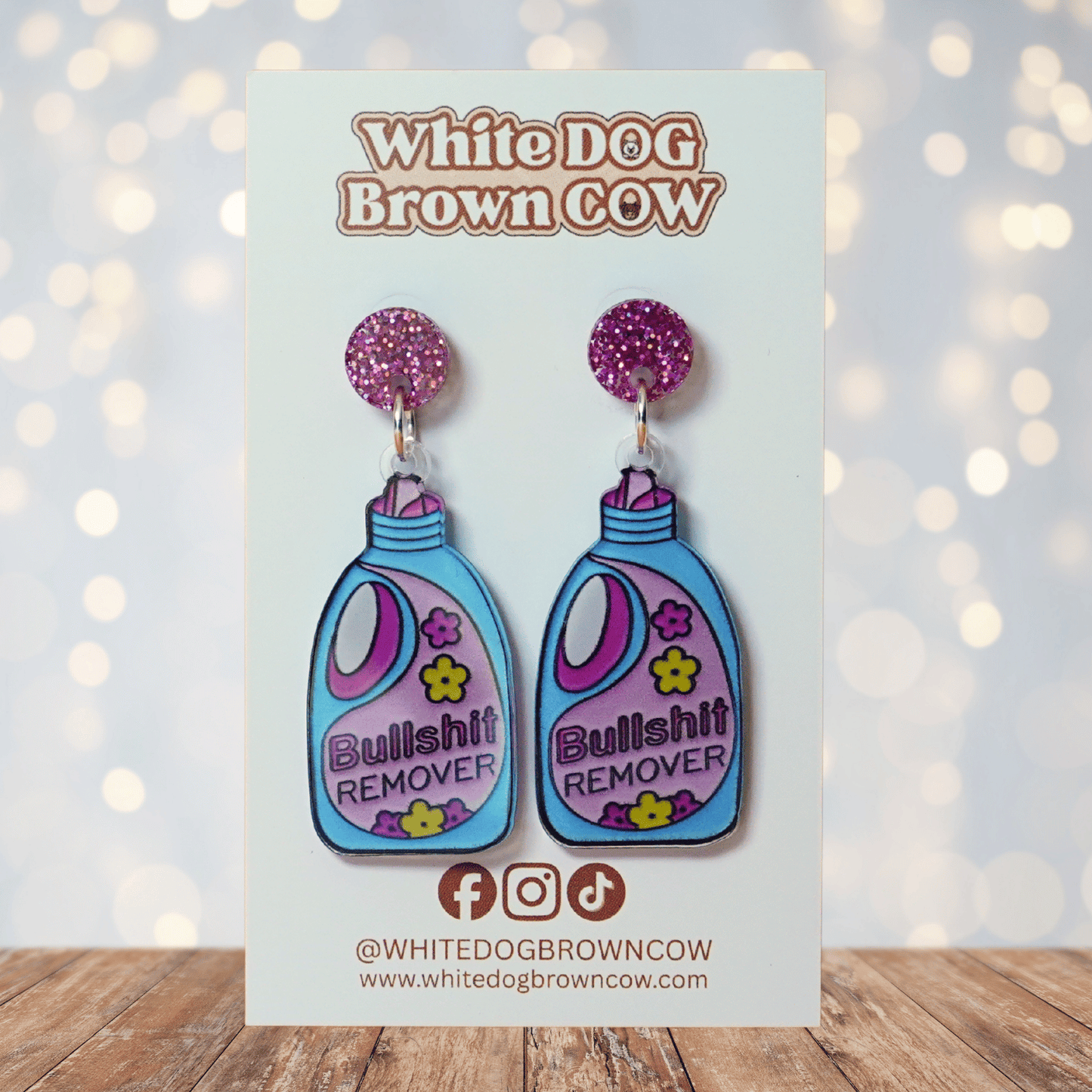Colorful novelty dangle earrings shaped like a detergent bottle labeled “Bullsh*t remover”