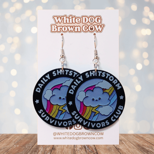 Round novelty dangle earrings reading “Daily Shitstorm Survivors Club” with a cute cloud, rainbow and lightning design