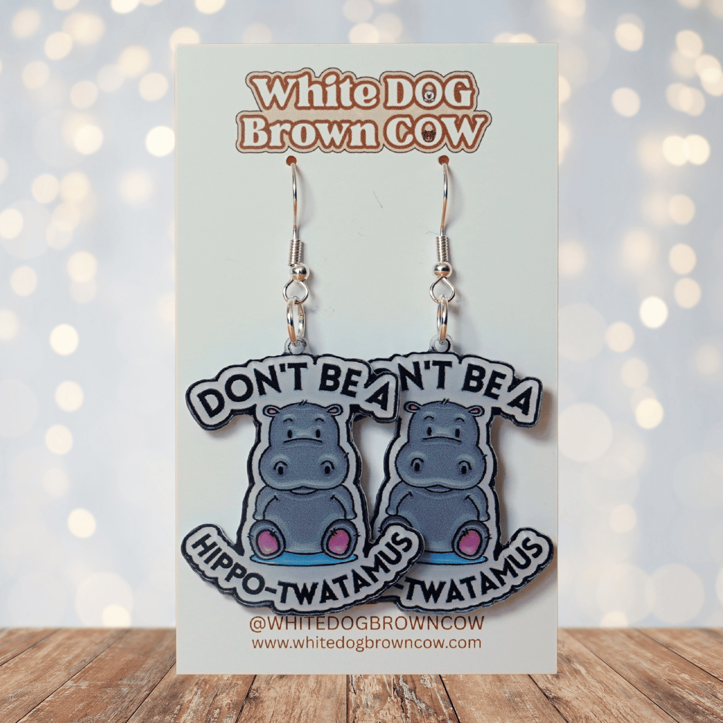 Novelty dangle earrings with a cute cartoon hippo and the phrase “Don’t be a hippo-twatamus”