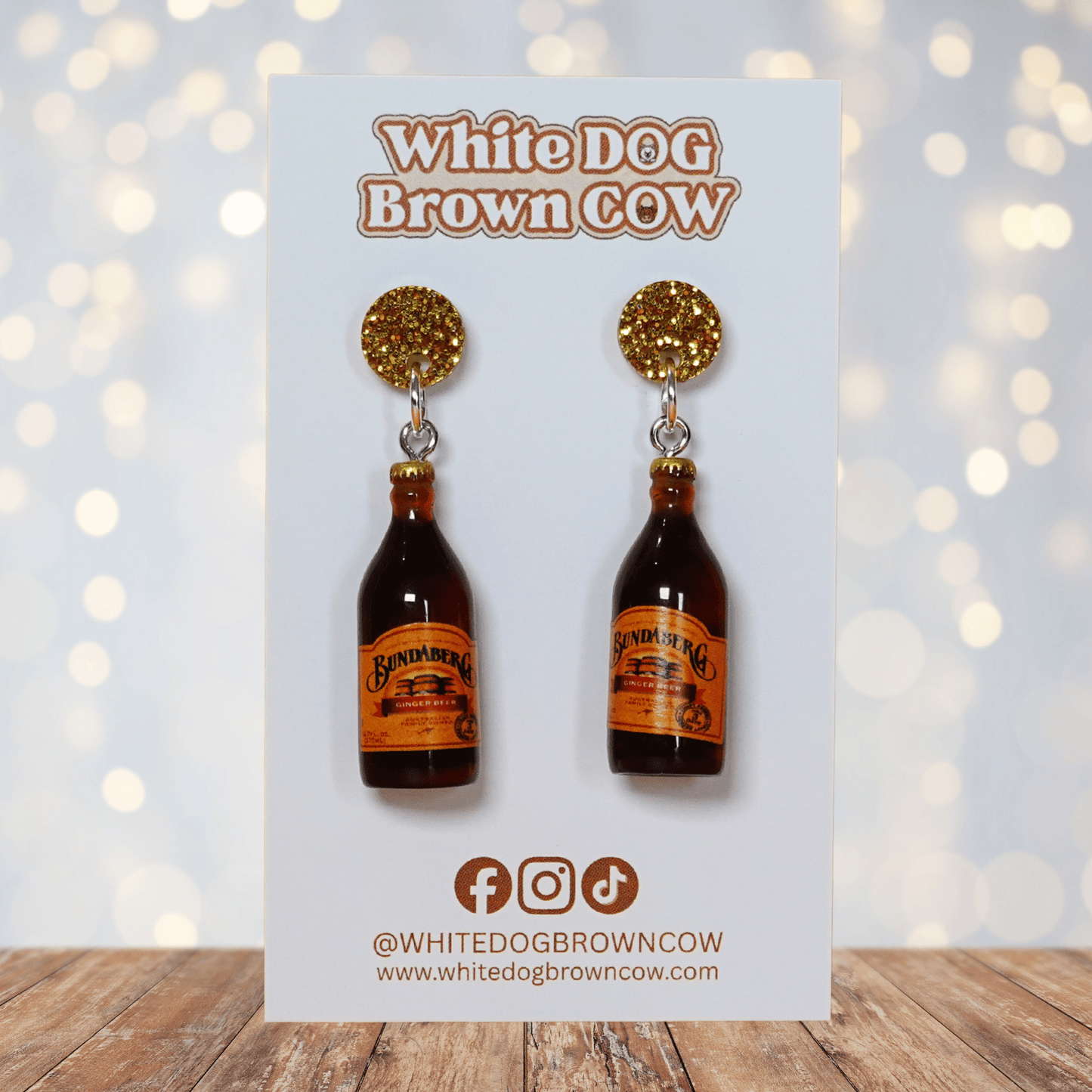 Mini brown ginger beer bottle shaped dangle earrings with orange labels and glitter studs