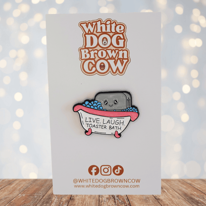 Funny dark humor enamel pin of smiling toaster in a bubble bath with text “live laugh toaster bath,” sarcastic novelty meme pin