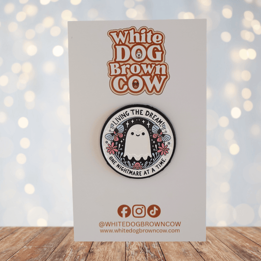 Cute ghost enamel pin with flowers and text “living the dream one nightmare at a time,” funny sarcastic spooky pin