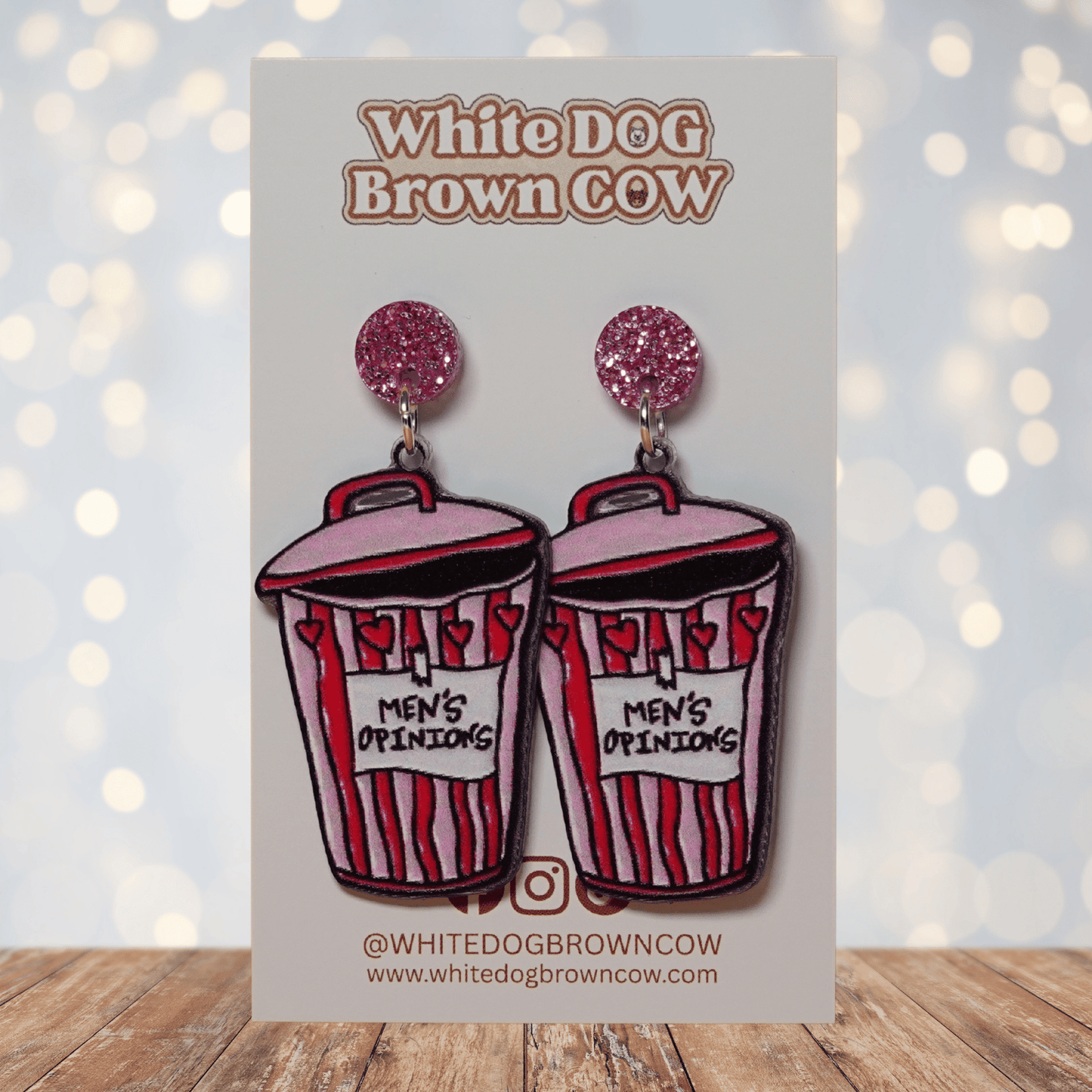 Acrylic dangle earrings shaped like a pink and red trash can labeled “Men’s Opinions”