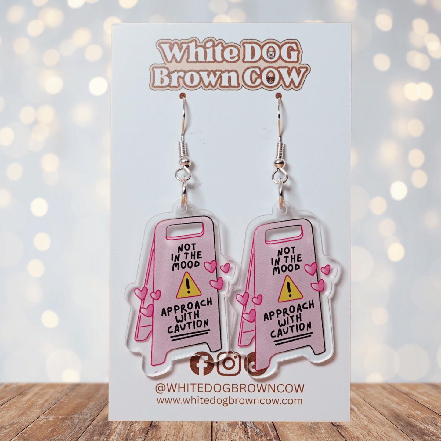 Funny acrylic dangle earrings shaped like a caution sign that reads “Not in the mood – approach with caution,” decorated with small pink hearts.