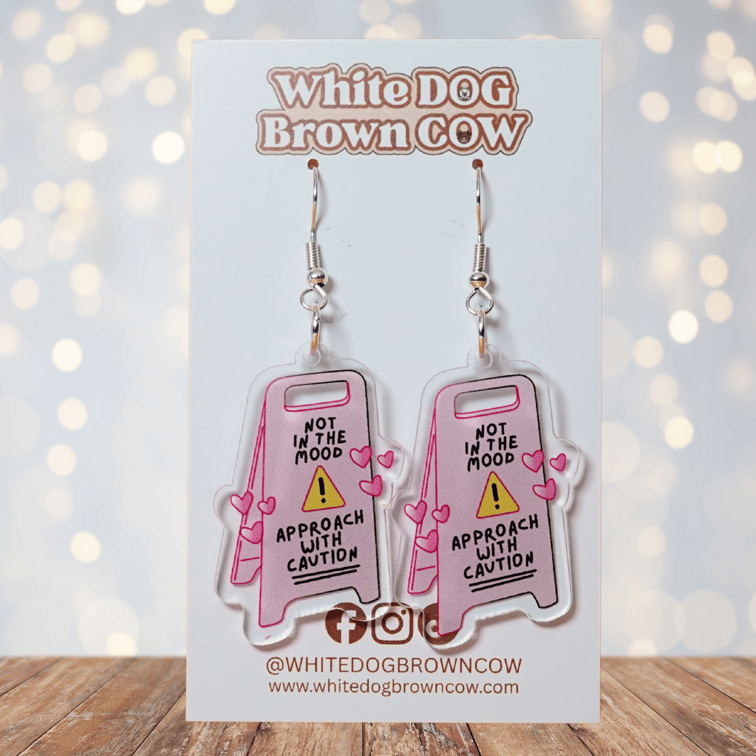 Funny acrylic dangle earrings shaped like a caution sign that reads “Not in the mood – approach with caution,” decorated with small pink hearts.