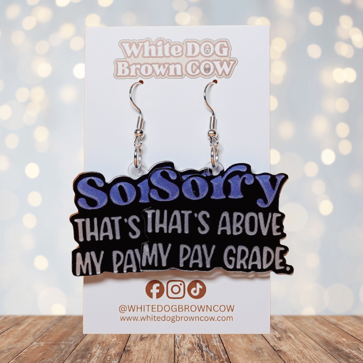 Black novelty dangle earrings with text “sorry that’s above my pay grade”