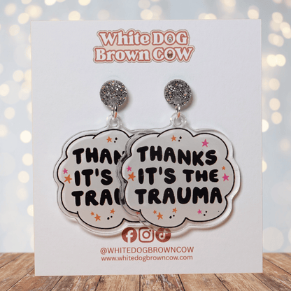 Clear acrylic dangle earrings with a speech bubble shape reading “Thanks it’s the trauma” with small star accents
