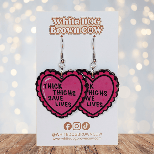 Pink heart dangle earrings with text “thick thighs save lives”