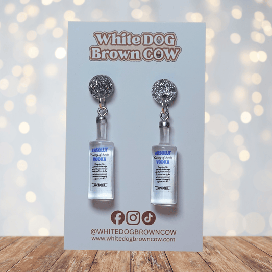 Novelty dangle earrings shaped like clear vodka bottles with a printed vodka-style label design.