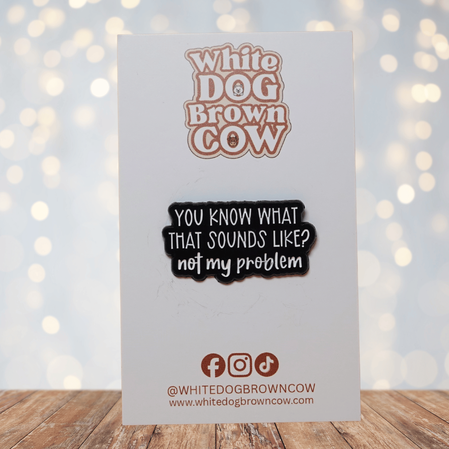 Black and white enamel pin reading “You Know What That Sounds Like? Not My Problem” in bold lettering, funny sarcastic office humor lapel pin.