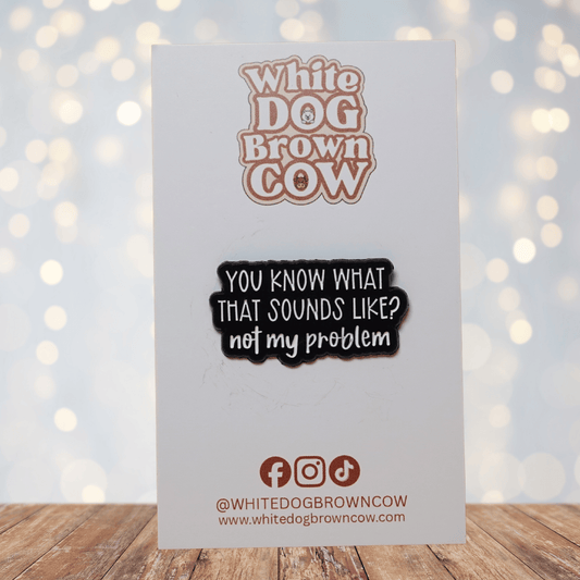 Black and white enamel pin reading “You Know What That Sounds Like? Not My Problem” in bold lettering, funny sarcastic office humor lapel pin.