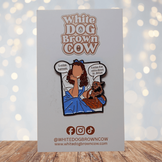 Enamel pin parody of Wizard of Oz with Dorothy and Toto saying “I miss Kansas” and “I miss the rains down in Africa,” funny pop culture mashup lapel pin.
